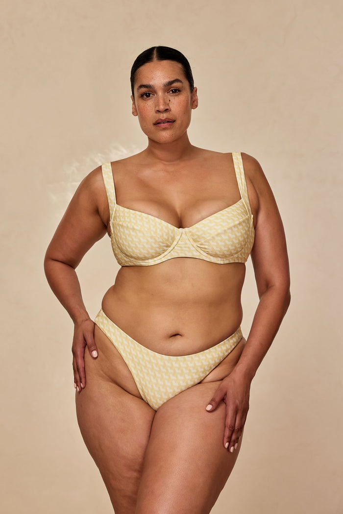 Front view of Tamarama Bottom in Ivory Geo showcasing cheeky coverage and high leg cut against beige background