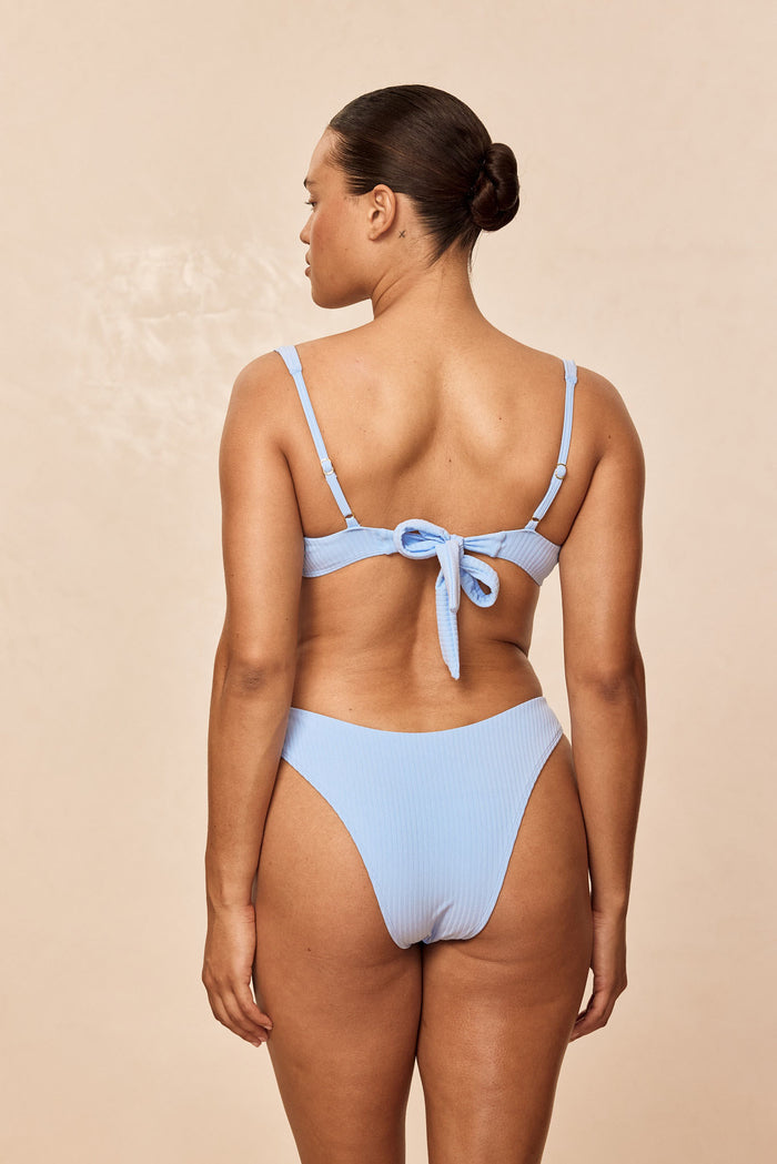 Back view of Sorrento Top in Sky Rib with ribbed texture, adjustable straps and tie-back closure on model