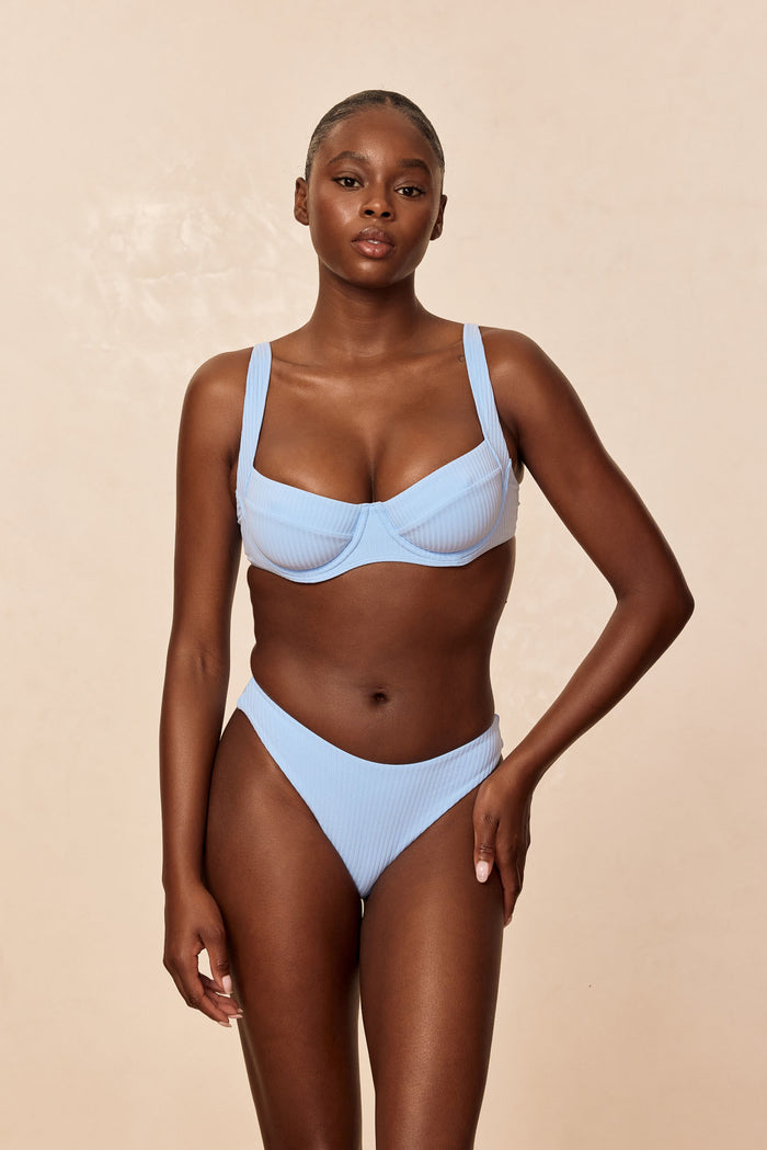 Front view of Sorrento Top in Sky Rib on model showing ribbed fabric, underwire cups and wide straps against beige background
