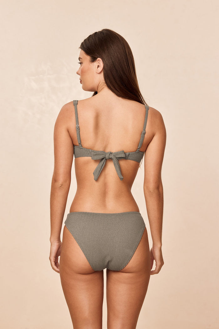 Rear view of Sorrento Top in Steel Lurex Rib showcasing tied back bow and adjustable shoulder straps on beige background