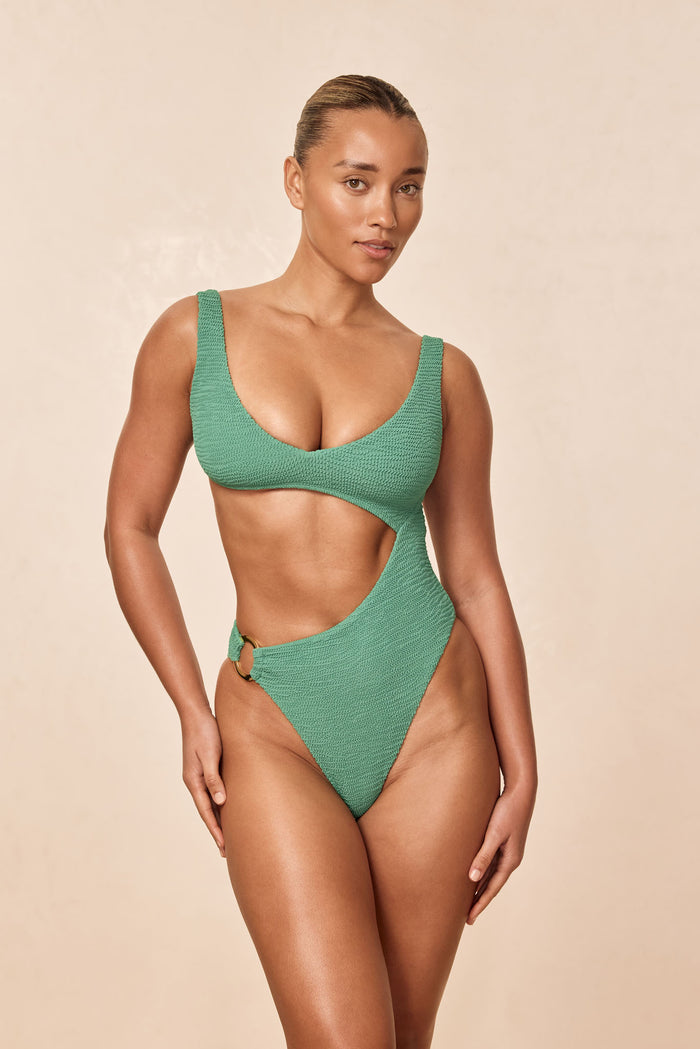 Front view of St. Barth's one-piece in pond crinkle showing textured fabric, waist cutout and gold ring on beige background