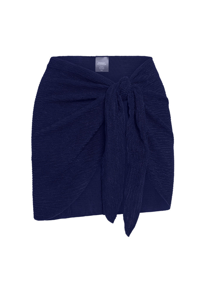 Cropped front view of St. Barth’s Skirt in Midnight Crinkle showing navy crinkle-knit sarong wrap with front tie on white background