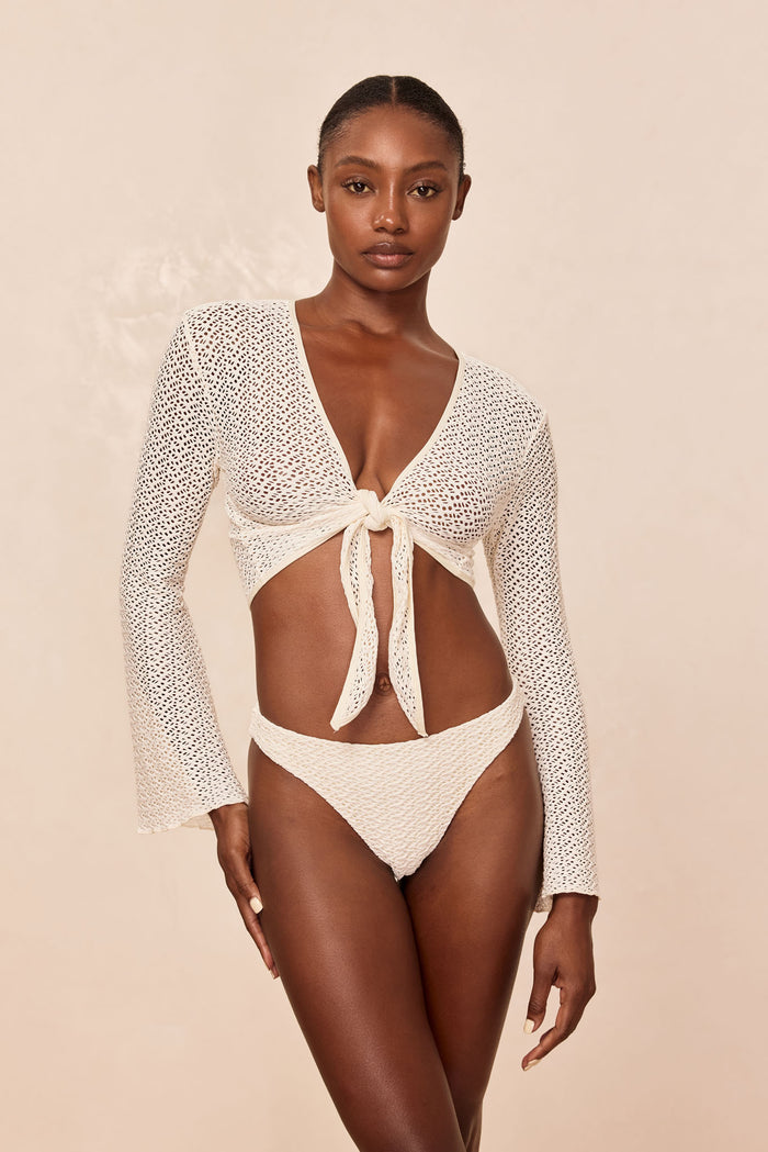 Front view of St. Barth's Top in ivory crochet showing tie-front V-neck, long sleeves, semi-sheer knit on beige background