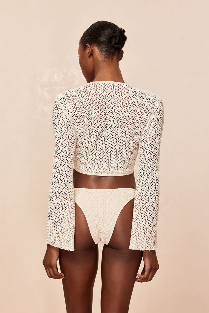 Back view of St Barth’s Top in ivory crochet showing long bell sleeves and semi-sheer open-knit on beige background