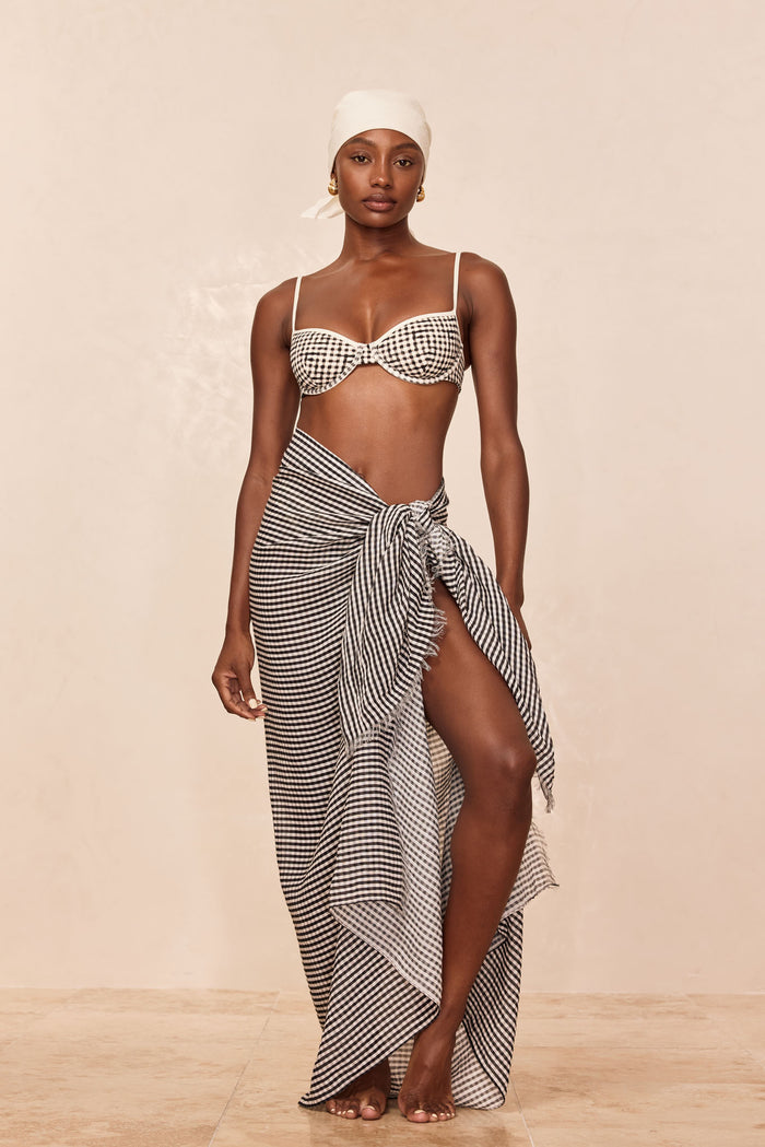 St Tropez Sarong in Black Gingham Crinkle tied at hip showing high side slit and frayed hem on beige backdrop