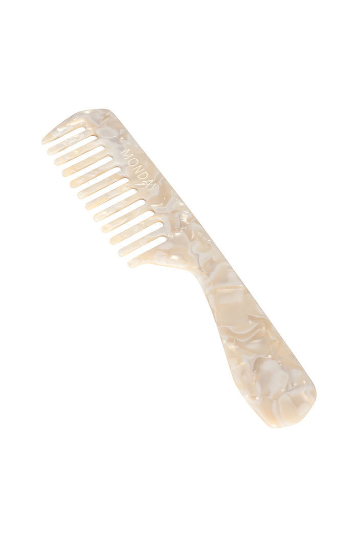 Angled view of Staniel Cay comb in ivory swirl showcasing wide teeth, marbled acetate finish, and engraved MONDAY logo on white background