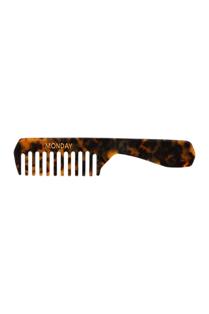 Tortoiseshell wide-tooth handled comb with MONDAY printed above the teeth