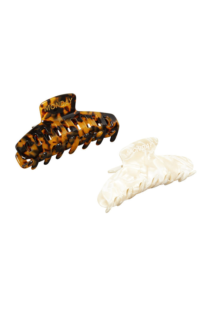 Two hair claw clips — tortoiseshell and pearlescent cream, each embossed with the word MONDAY