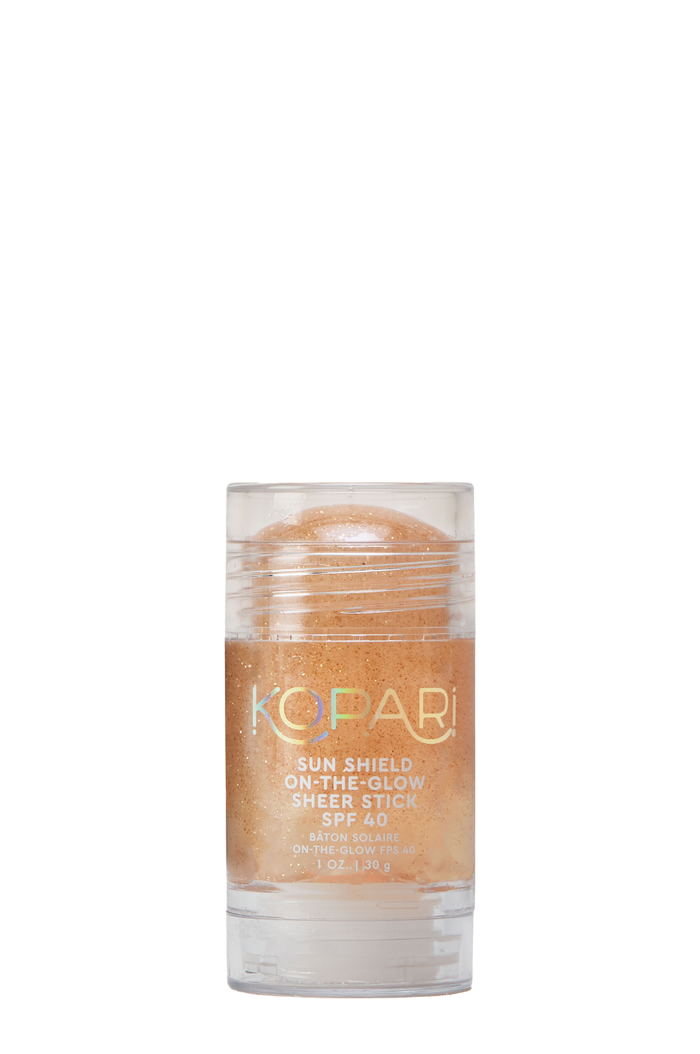 Front view of Kopari Sun Shield Sheer Stick SPF 40 showing golden shimmer in a clear plastic tube on white background