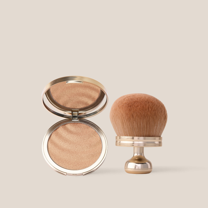 Front view of Sun Veil Illuminating Sunscreen SPF 30 compact open showing shimmering bronzer and kabuki brush on beige