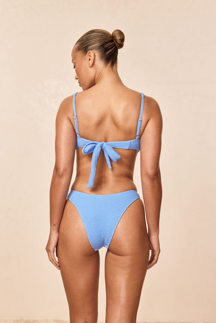 Back view of Barbuda Top in Azure Crinkle showcasing adjustable back tie and textured fabric on a neutral beige background