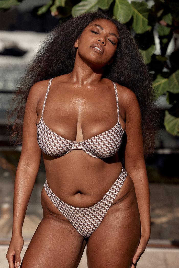 Front view of Tamarama Bottom on model showcasing Husk Geo brown-and-white geometric print and high-cut leg in outdoor setting