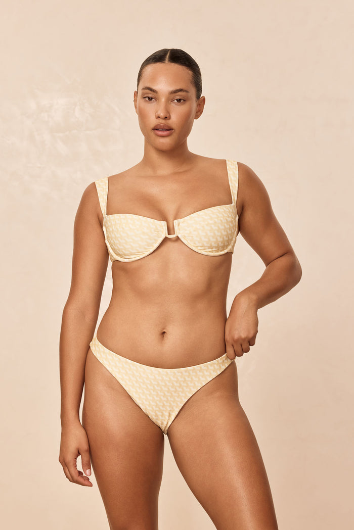 Front view of Tamarama Bottom in Ivory Geo showcasing cheeky mid-rise coverage and high-leg cut on model against a beige background