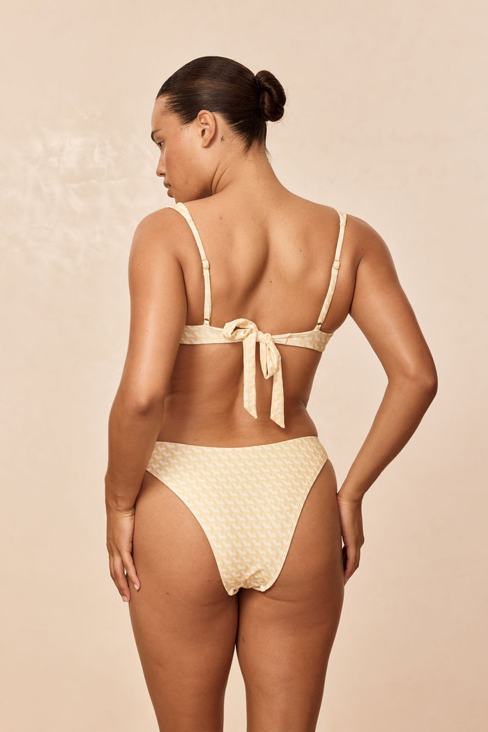 Back view of Tamarama Bottom in Ivory Geo showcasing cheeky coverage and high leg cut on a neutral beige background