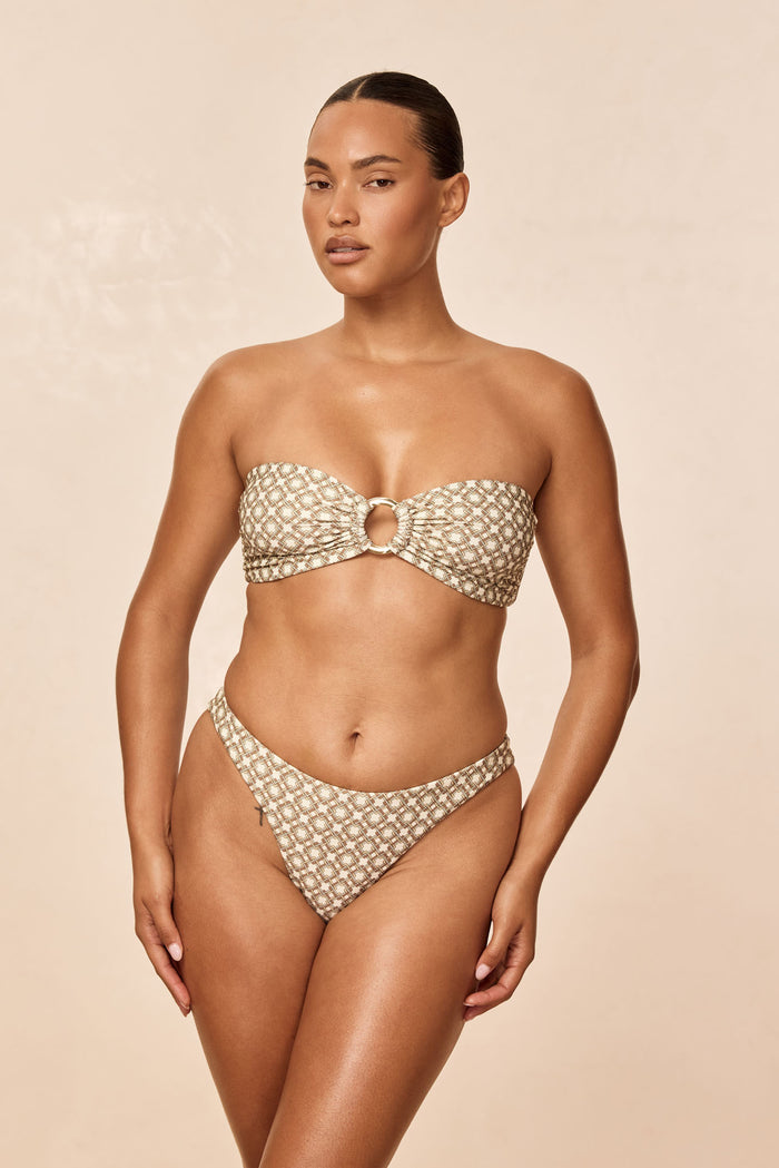 Front view of Tamarama Bottom Tile Geo showcasing high leg cut, thin sides and cheeky mid-rise fit on beige backdrop