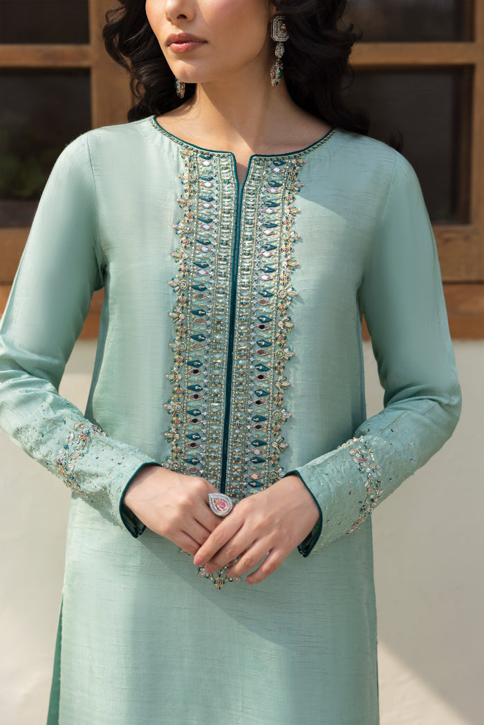 NAQSHI Tania showing fluid straight shirt, contrast teal piping along sleeves, and peek of embroidered culottes below.