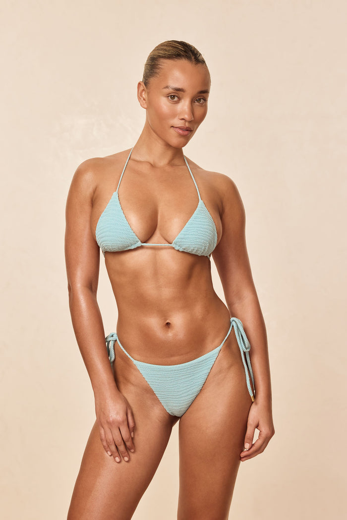 Front view of Taormina Bottom in Light Slate Crinkle on a model showcasing textured crinkle fabric and side-tie details against a beige studio background