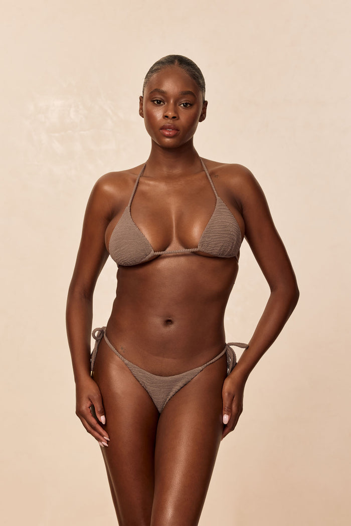 Front view of Taormina Bottom in Stone Crinkle showcasing low-rise fit with adjustable tie sides on beige background