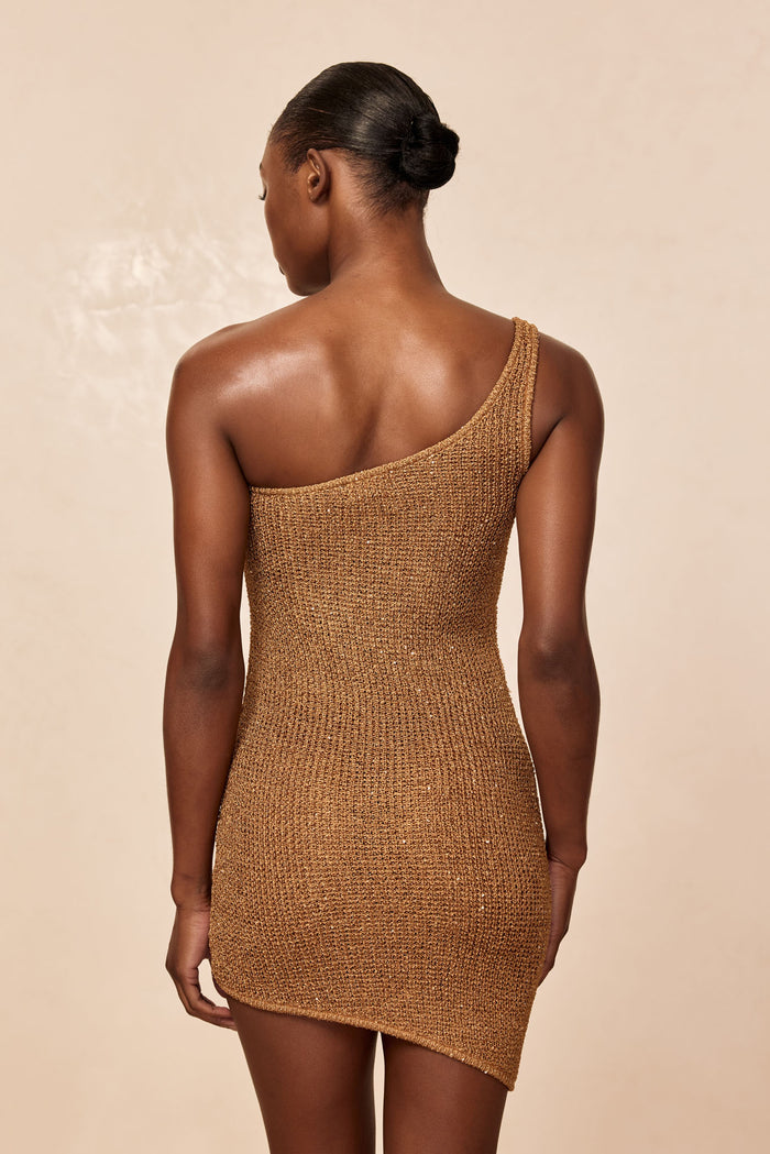 Back view of Taormina Dress in antique gold sequin knit showing one shoulder, fitted silhouette, and asymmetric mini hem