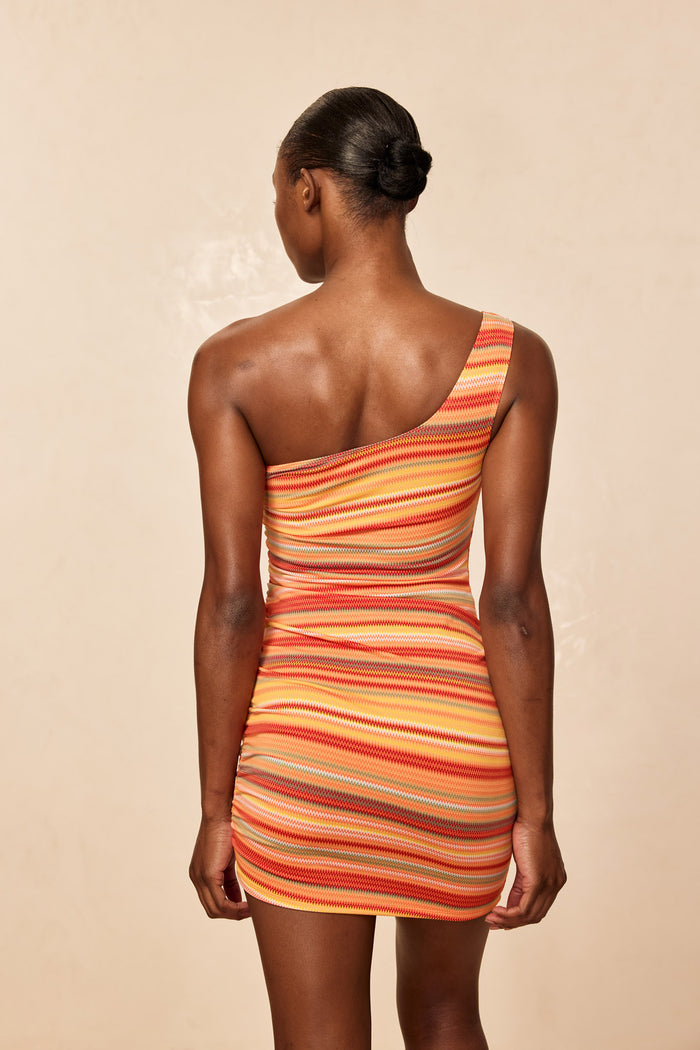 Back view of Taormina Dress in Sardinia Stripe, one-shoulder fitted ruched mini on beige background
