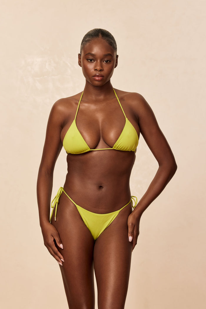 Front view of Taormina bottom in Apple on model showcasing low-rise tie sides and moderate cheek coverage with beige studio background