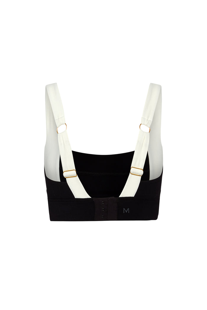 Back view of black sports bra with adjustable white straps and metal rings, size marking M on band