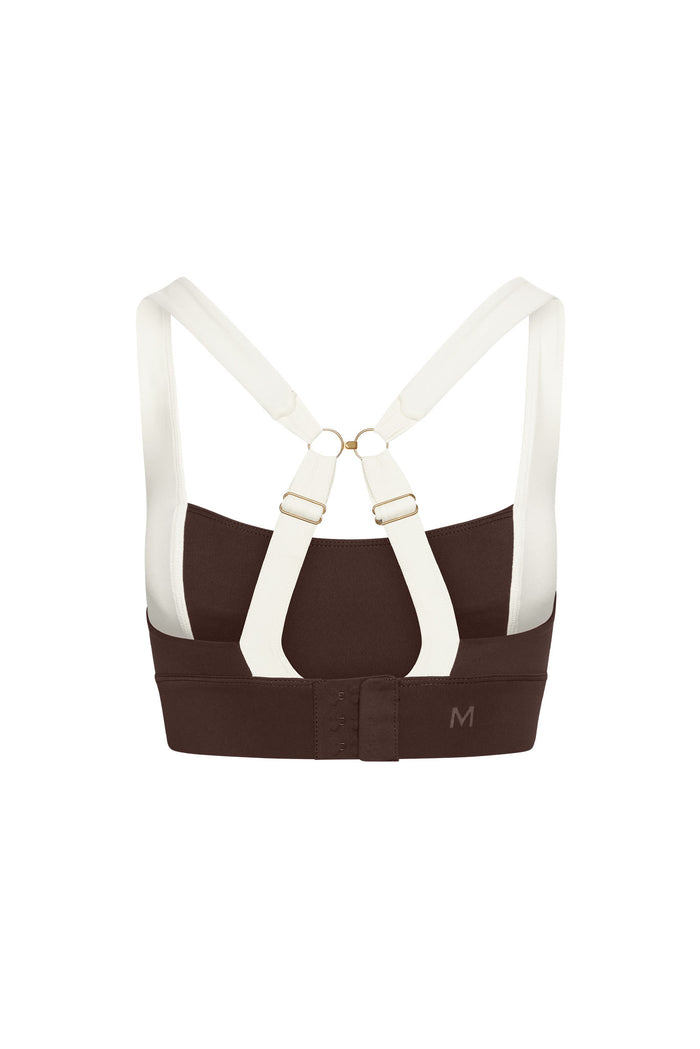 Brown sports bra back with white crossover straps, gold rings, hook-and-eye closure and M size mark