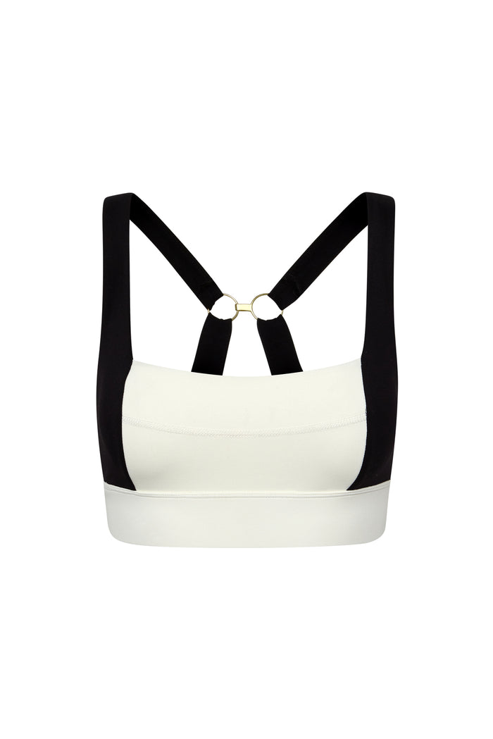 White sports bra with black crossover straps and gold-ring back detail