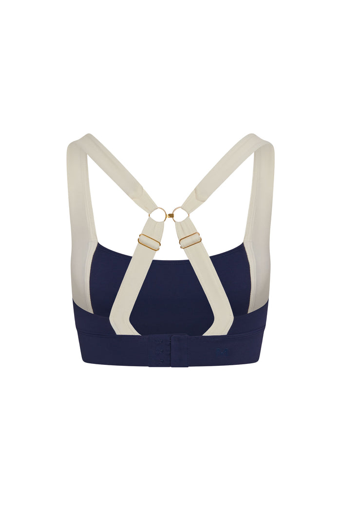 Back view of Tash Bra in midnight and ivory with crossed adjustable straps, gold rings and hook-and-eye closure on white