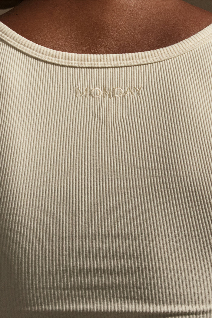 Close-up back of Tash Tank Long in ivory rib showing MONDAY embroidered label and fine rib texture on model’s upper back