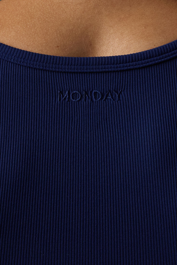 Close-up of back of Tash Tank in Midnight showing thin rib texture and embroidered MONDAY logo against model skin