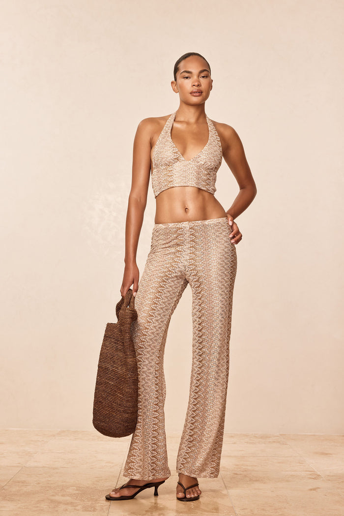 Front view of Toulon Pant Porto Cervo Gold showcasing fitted crochet knit and flared leg on model against a beige studio background