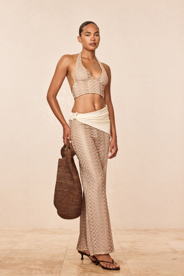 Front view of Toulon Top, Porto Cervo Gold halter crop with deep V neckline and textured crochet knit on beige background