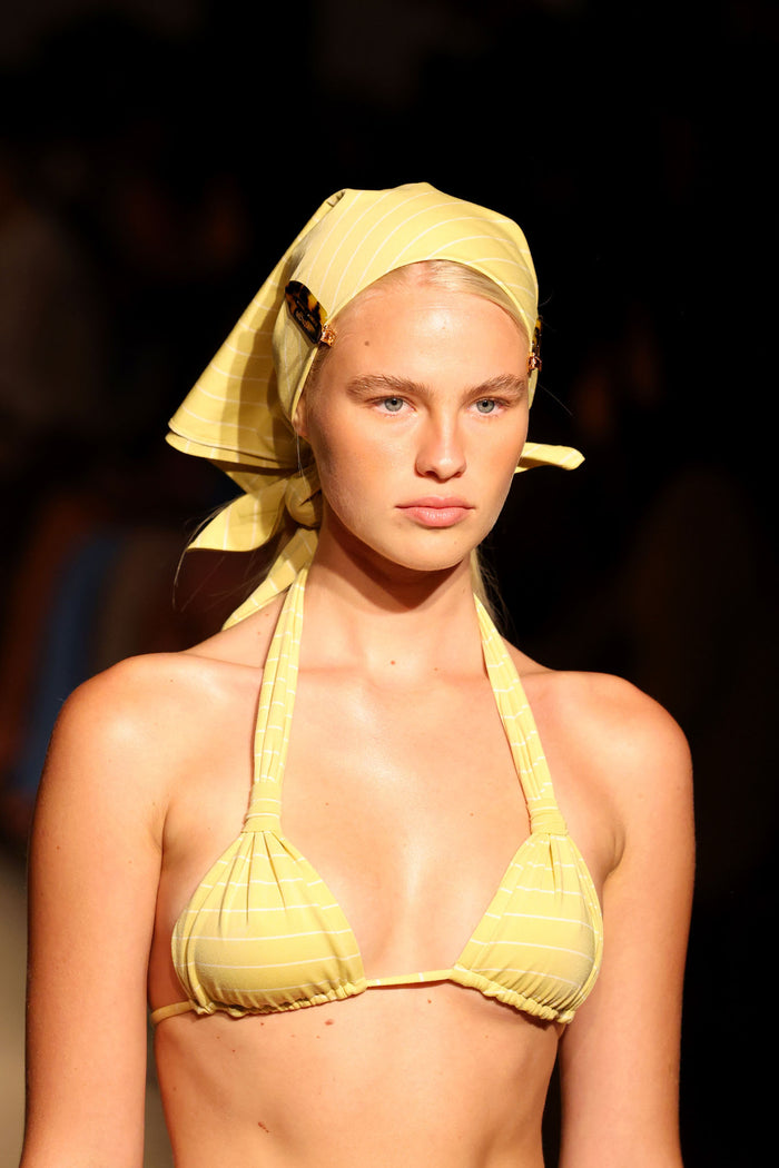 Front of Tulum Top - Meyer Stripe showcasing pleated cup detail, gold ring and adjustable ties on dark runway background