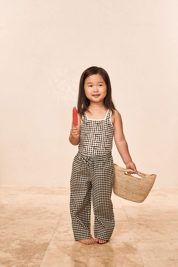 Front of Corfu One Piece Kids black gingham showing square neckline on toddler model holding red popsicle and basket