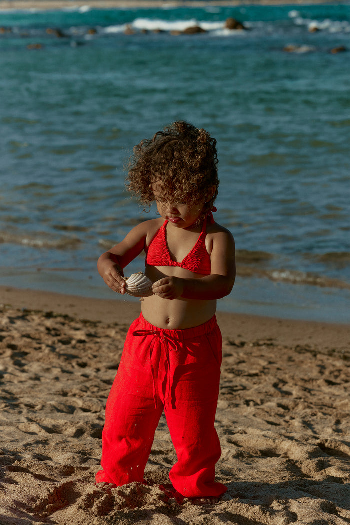 Front view of Tuscany Pant Kids pant in Chili Pepper showcasing relaxed fit and drawstring waist on a toddler at the beach