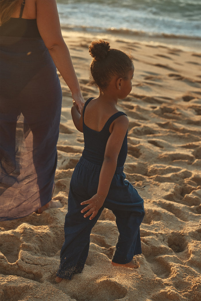 Rear view of Tuscany Pant Kids in Midnight showing relaxed wide-leg fit and elastic waistband on sandy beach at sunset