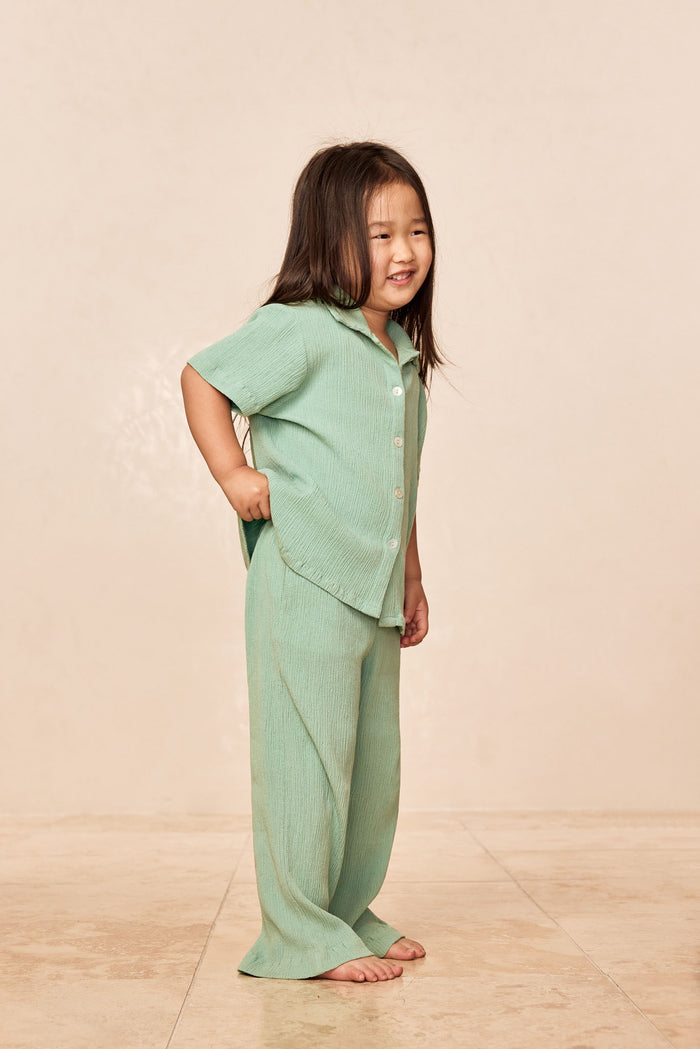 Three-quarter view of Tuscany Pant Kids in Pond Crinkle showcasing flare leg and crinkle texture on neutral studio background