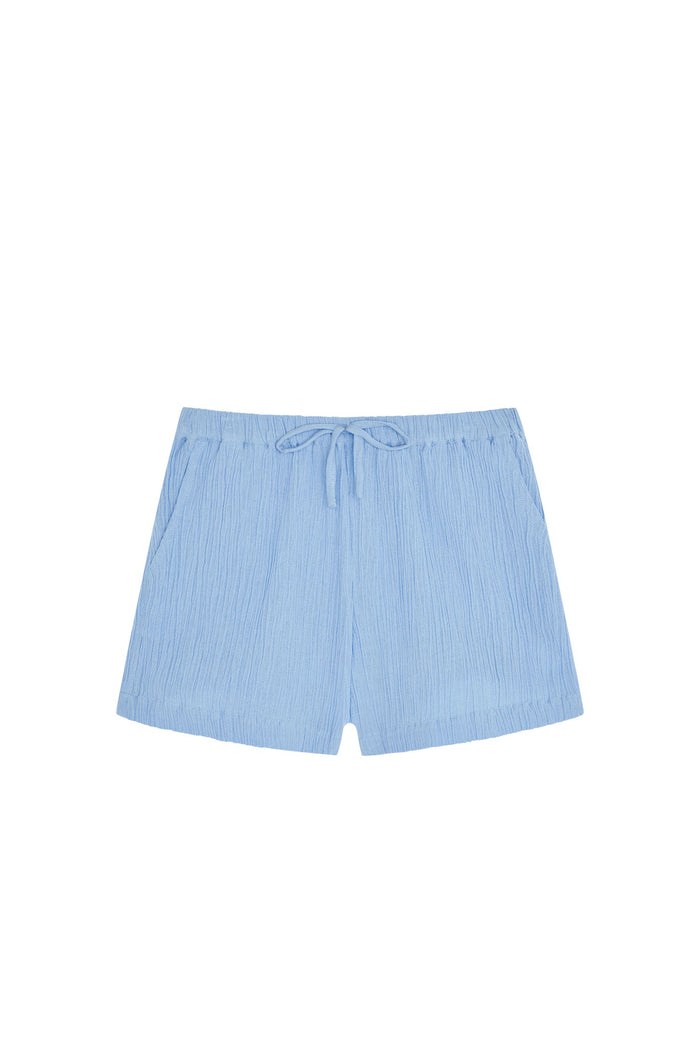 Front flat lay of Tuscany Short Kids in sky blue showcasing crinkle texture, elastic waist with faux tie and side pockets on white background