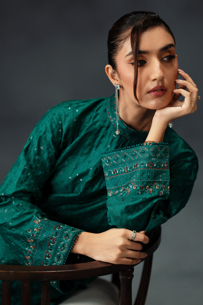 Styled presentation of NAQSHI Zahra emerald green formal outfit with fine embroidered patterns on premium fabric for celebration events