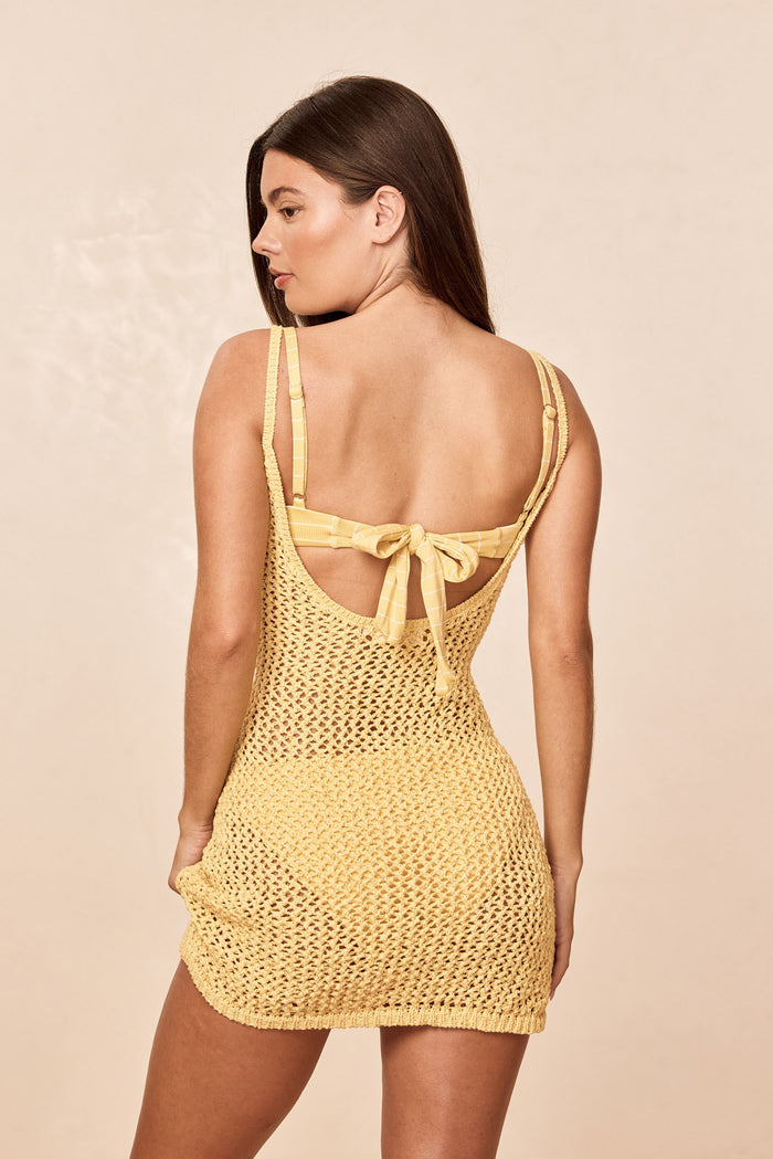Rear view of Zanzibar Mini Dress Meyer Petit Crochet showcasing low scoop back with tied bow and yellow crochet knit on neutral background