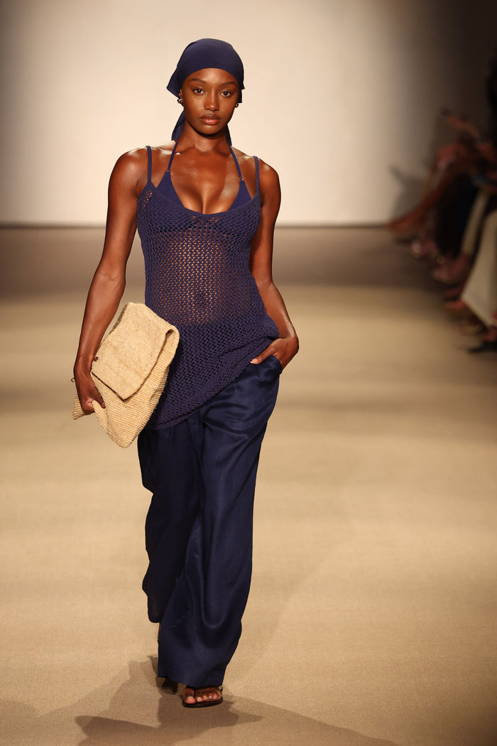Runway model walking in Zanzibar Mini Dress in Midnight Petit Crochet, relaxed fit over bikini, holding woven clutch