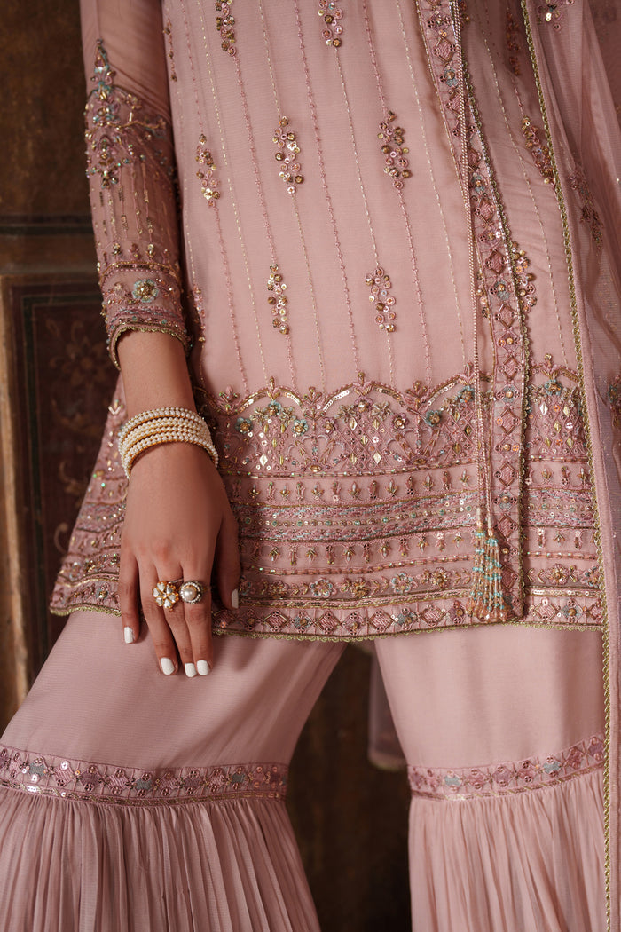 Close-up of a pink embroidered traditional outfit with intricate designs.