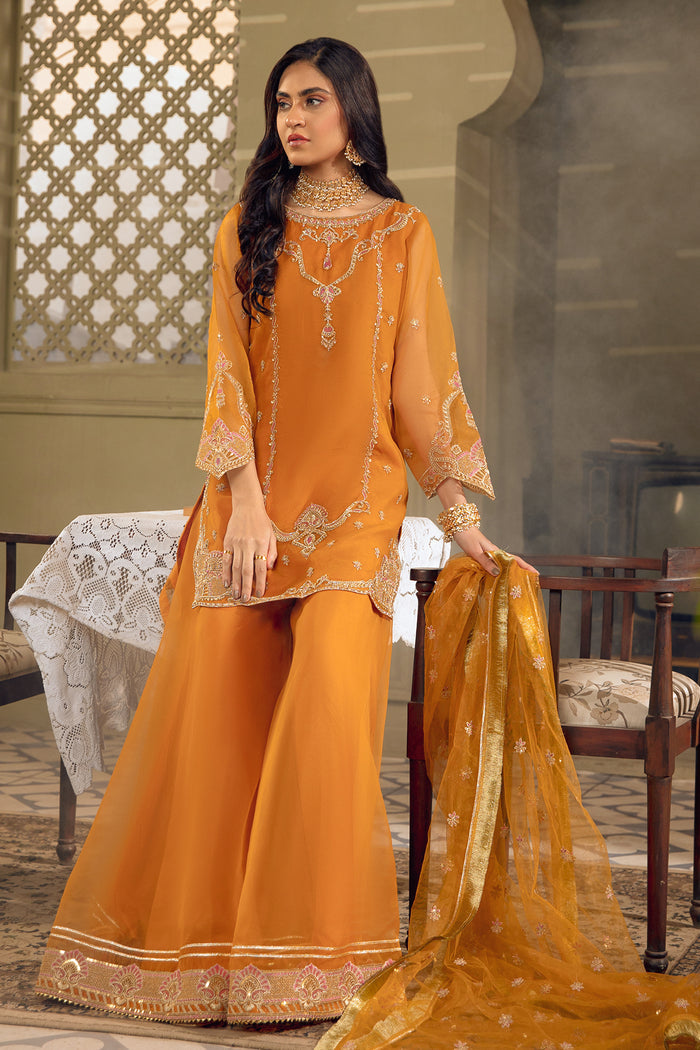 Full front standing view of NAQSHI Zaryaab outfit showing mustard orange short shirt, flowing sharara, and elegant festive look