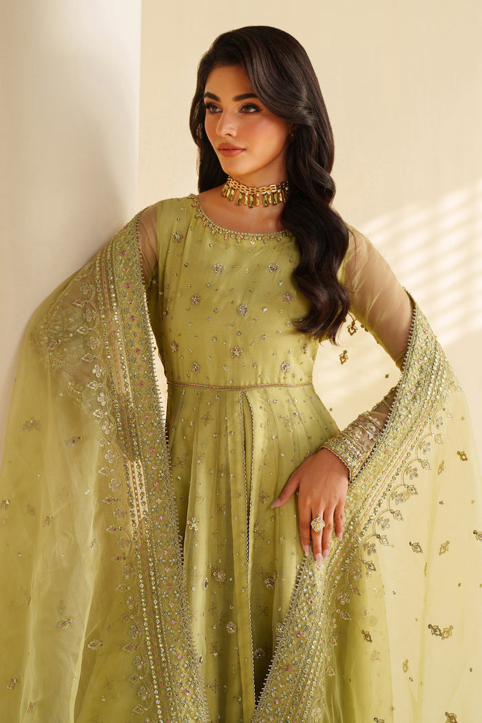 Woman wearing a green embroidered traditional outfit with a matching dupatta.
